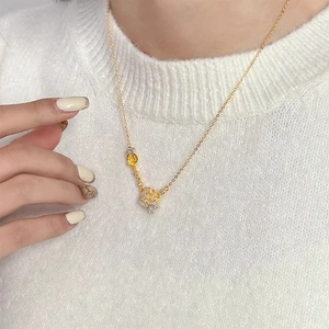 Elegante collana dorata con doppia rosa e cristalli su sfondo in maglia bianca