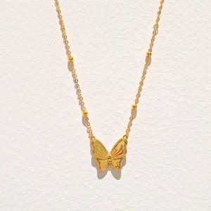 Détail du collier papillon doré élégant avec ailes texturées et chaîne à billes fines