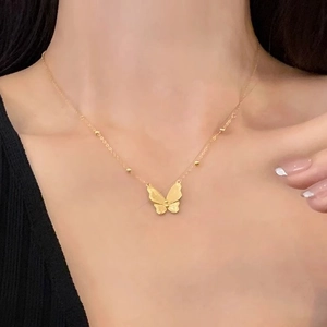 Collier papillon doré élégant avec petites perles sur chaîne fine porté par un mannequin