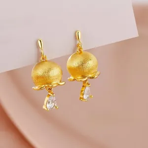 Close-up of matte gold lily of the valley earrings with a teardrop zircon crystal