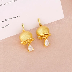 Golden lily of the valley earrings with teardrop zircons on a decorative background