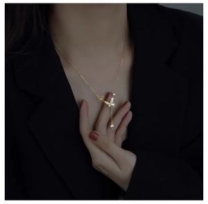 Detailed view of a gold butterfly necklace with zircon paving, pearl, and tassel elements