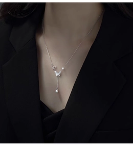 Detail of silver butterfly pendant necklace with pearls on elegant business attire