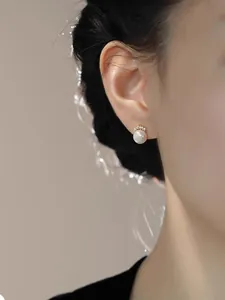 Detail of elegant pearl earring with gold crown setting and micro diamonds on ear