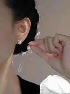 Close-up of pearl stud earrings featuring a golden crown mount and fine diamond accents