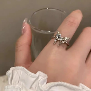 Detailed view of silver butterfly ring with purple crystals worn on the index finger