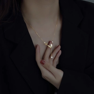 Elegant gold butterfly necklace with pearls on a model wearing a black blazer