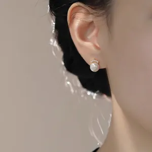 Elegant pearl stud earrings with gold crown setting and cubic zirconia on model