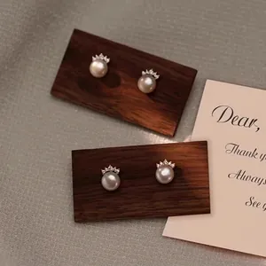 S925 silver freshwater pearl stud earrings with crown cubic zirconia on a wooden display