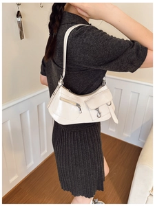 Detail of cream patent leather hobo bag featuring silver buckles and functional pockets