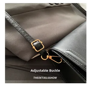 Close-up of golden adjustable buckle and stitching detail on the black leather shoulder strap