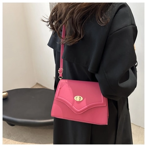 Detail of a bright pink shoulder bag featuring a gold oval twist-lock and V-shaped flap