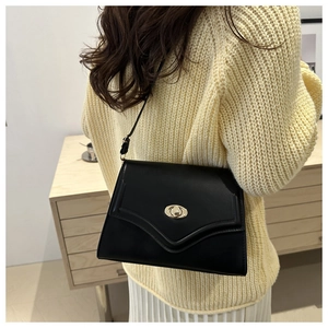 Side view of a black minimalist leather crossbody bag with a vintage gold metal lock