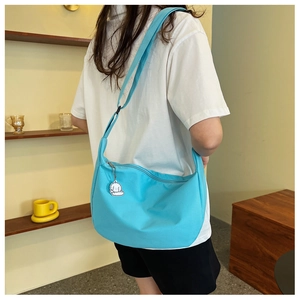 Détail du sac bandoulière croissant bleu avec un petit pendentif de chien blanc pur