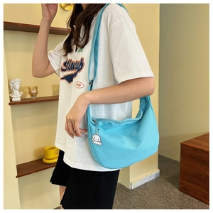 Détail du sac hobo bleu clair avec un joli pendentif de chiot blanc et une bandoulière