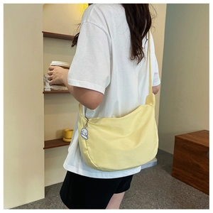 Détail du sac besace en toile jaune clair avec pendentif chiot et large bandoulière