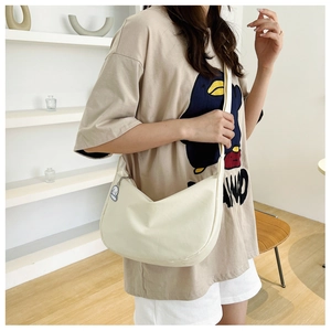 Détail du sac bandoulière croissant blanc cassé avec un pendentif peluche chiot