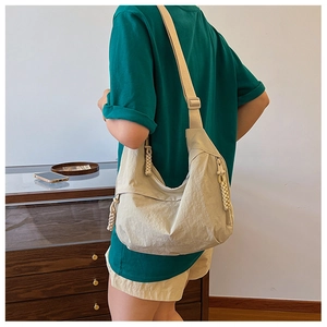 Detalle del bolso de nailon beige arrugado con correa ancha y tirador de cremallera