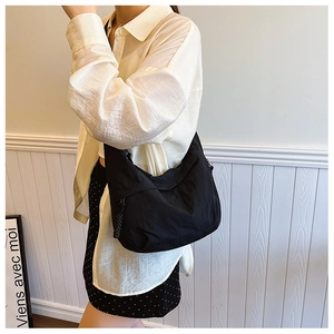 Detalle de un bolso hobo de nailon negro con un tirador de cremallera tejido decorativo