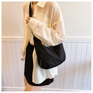 Detalle del bolso hobo de nailon negro con correa ancha y tirador de cremallera tejido
