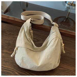 Detalle de bolso bandolera de nailon beige con cremallera de cuerda y bolsillo lateral