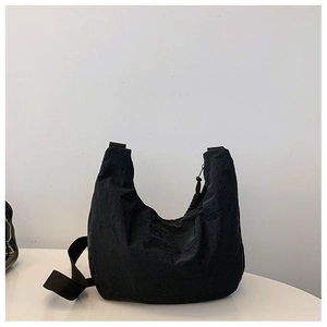 Detalle del bolso de media luna en nailon negro con textura ligera y correa de lona