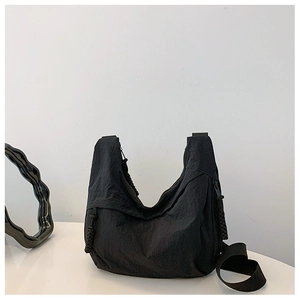 Detalle del bolso media luna de nailon negro plisado con tirador de cremallera trenzado