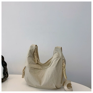 Detalle del bolso media luna de nailon beige con tiradores de cremallera tejidos