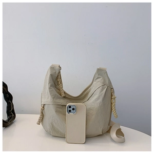 Bolso bandolera de nailon crema junto a un smartphone para comparar el tamaño real