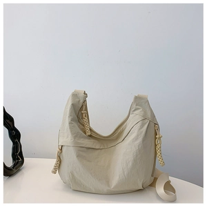 Detalle de la tela de nailon arrugado beige y el tirador trenzado en el bolso media luna