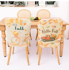 Detail of Hello Fall chair covers with pumpkin and maple leaf prints for dining room decor