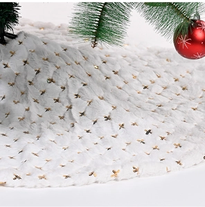 Close-up of white plush Christmas tree skirt with shimmering gold sequins for party decor