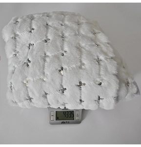 Close-up of white faux fur Christmas tree skirt with silver sequins showing 433g weight