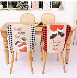 Close-up of linen Santa STOP HERE chair covers with festive plaid trim in a dining room