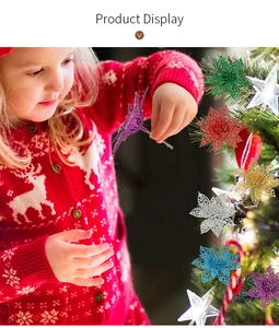 Enfant décorant un sapin de Noël avec des fleurs artificielles à paillettes colorées