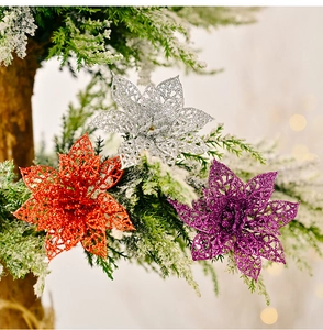 Gros plan de fleurs de Noël ajourées à paillettes rouges, argent et violettes sur branches