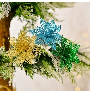 Gros plan de fleurs de Noël creuses à paillettes sur des branches de sapin enneigées