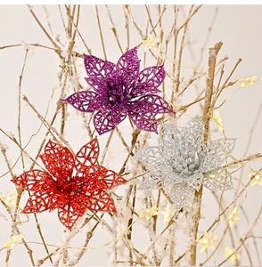 Détail de fleurs de Noël artificielles scintillantes et ajourées sur branches enneigées