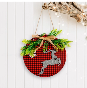 Close-up of a rustic Christmas door sign with red buffalo plaid, silver reindeer and greenery