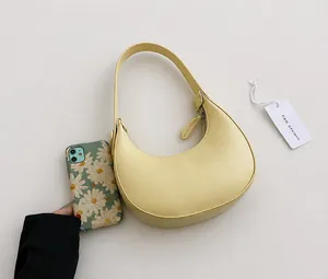 Detail view of a pale yellow crescent hobo bag with a phone for size reference