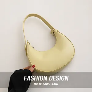 Detail view of a pale yellow crescent underarm bag with smooth PU leather texture