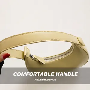 Detail view of the yellow leather crescent bag with silver zipper and wide handle strap