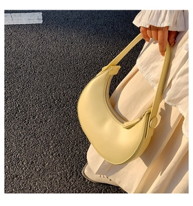 Detailed view of yellow crescent shoulder bag with smooth leather finish and zipper
