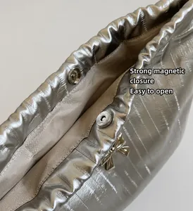 Dettaglio macro della borsa argento con chiusura magnetica e decorazione a fiocco