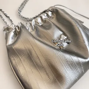 Dettaglio della borsa tote in pelle argentata con fiocco metallico e tracolla a catena