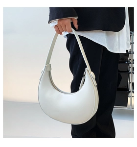 Close-up of white minimalist hobo bag showing silver zipper and textured leather finish