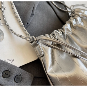 Dettaglio della borsa a secchiello metallizzata argento con catena e texture plissettata