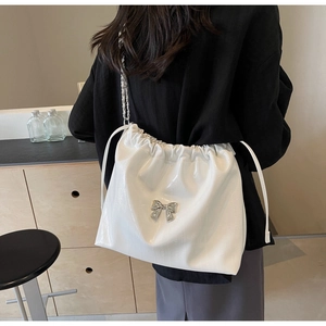 Dettaglio borsa tote bianca lucida con chiusura a coulisse e fiocco in metallo argento