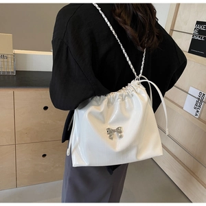 Dettaglio della borsa tote in pelle verniciata bianca con fiocco e tracolla a catena