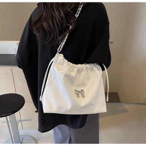 Dettaglio borsa bianca in pelle increspata con fiocco argento e tracolla a catena